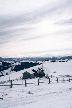 Yumuşak, karla kaplı tepeler, kırsal bir çiftlik evi ve çitlerle çevrili ahırlar içeren geniş bir kış manzarası. Gökyüzü bulutlu ve sahneye yumuşak, barışçıl bir ton ekliyor. Temalar için mükemmel