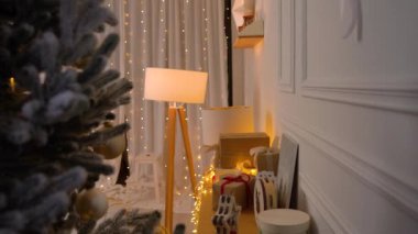 Güzel dekore edilmiş bir Noel iç mimarisi. İçinde şenlikli hediye kutuları, sıcak ip ışıkları ve ön planda bir Noel ağacı var. Yumuşak ışıklandırma ve zarif dekor rahat bir tatil ortamı yaratır..
