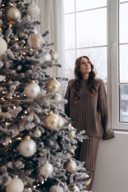 Güzel dekore edilmiş bir Noel ağacının yanında altın süslemelerle duran bir kadının neşeli tatil atmosferini kucakladığı huzurlu bir an..