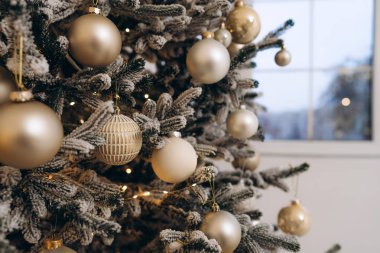 Detailed close-up of a beautifully decorated Christmas tree adorned with golden and white ornaments, frosted branches, and warm fairy lights. A serene holiday ambiance. clipart