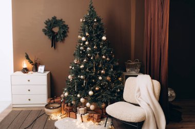 Altın ve bronz süslemeler, peri ışıkları ve çam kozalaklarıyla süslenmiş güzel dekore edilmiş bir Noel ağacı. Paketlenmiş hediyeler altında oturur, sıcak tatil atmosferini tamamlar..