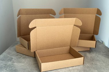 Üç Kraft karton kutu, beton bir yüzey üzerinde açık kapaklar sergileniyor. E-ticaret, ambalaj kavramları ya da çevre dostu ürün depolama fikirleri için mükemmel.