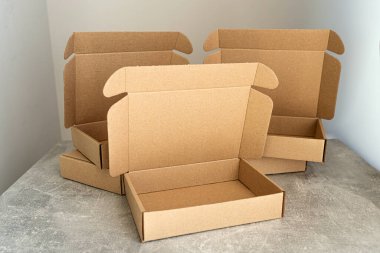 Üç Kraft karton kutu, beton bir yüzey üzerinde açık kapaklar sergileniyor. E-ticaret, ambalaj kavramları ya da çevre dostu ürün depolama fikirleri için mükemmel.