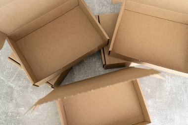 Üç Kraft karton kutu, beton bir yüzey üzerinde açık kapaklar sergileniyor. E-ticaret, ambalaj kavramları ya da çevre dostu ürün depolama fikirleri için mükemmel.