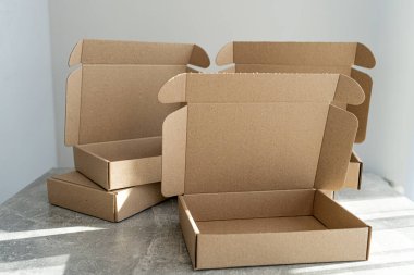 Doğal ışıklandırmada desenli beton bir masada açık flaplı üç Kraft mukavva kutu. Küçük işletmeler için sürdürülebilir ambalaj ya da nakliye malzemelerini göstermek için ideal.