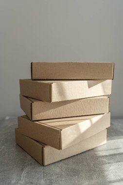 Kendi kendine monte edilen kraft karton kutular desenli bir yüzeye yerleştirilmiş. Paketleme, hediye paketleme ve nakliye için ideal. İşletmeler ve tatil hazırlıkları için sürdürülebilir bir seçim.