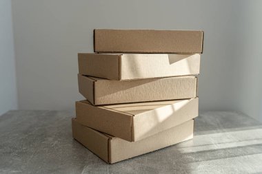 Kendi kendine monte edilen kraft karton kutular desenli bir yüzeye yerleştirilmiş. Paketleme, hediye paketleme ve nakliye için ideal. İşletmeler ve tatil hazırlıkları için sürdürülebilir bir seçim.