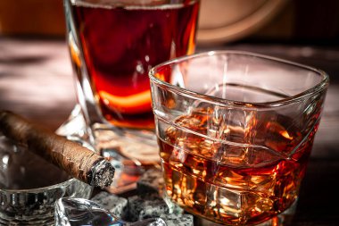 A gA glass of scotch whiskey with ice and a cigar on a wooden table close-up. Food photo.