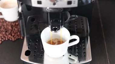 Modern bir kahve makinesi, metalin üzerinde duran beyaz bir fincana lezzetli bir kahve koyar, yakın plan. Kahve..