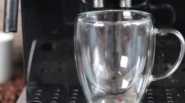 Modern bir kahve makinesi, metal destekte duran şeffaf bir fincana lezzetli bir kahve koyar, yakın plan. Kahve..