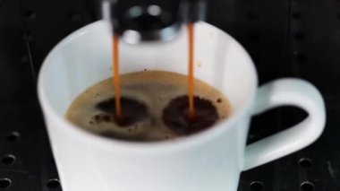Modern bir kahve makinesi, metalin üzerinde duran beyaz bir fincana lezzetli bir kahve koyar, yakın plan. Kahve..