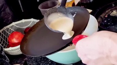 Bir kadın tavaya krep hamuru döker. Krepler tavada kızarır. Ev yapımı Rus krepleri pişirme süreci. Krepten duman yükselir. Yemek pişirme.