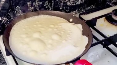 Kızartma tavasında büyük yuvarlak bir gözleme. Krepten duman yükselir. Delikli gözleme. Maslenitsa. Rus geleneği. Yemek pişirme.