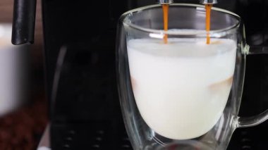 Sütlü cam bardağa doldurulan kahvenin yakın plan çekimi, otomatik kahve makinesiyle kapuçino yapmak. Kahve..