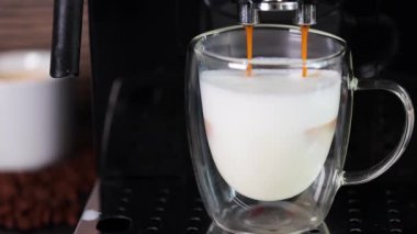 Sütlü cam bardağa doldurulan kahvenin yakın plan çekimi, otomatik kahve makinesiyle kapuçino yapmak. Kahve..