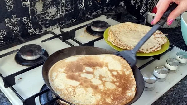 Large round pancake in a frying pan. Cooking smoke rises from the pancake. Pancakes with holes. Maslenitsa. Russian tradition. Cooking.