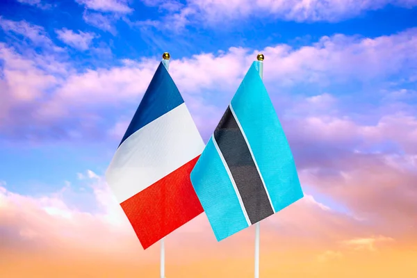 National flags of France and Botswana against the sky at sunset. Flags.