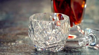 Buz küpü bir bardak viskinin içine düşer. Ağır çekim. Ağır çekimde, viski ahşap bir masaya sıçrar. Viski..