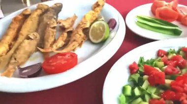 Kadın elleri kafede kızarmış balığın üzerine limon suyu sıkıyor. Yemek videosu.