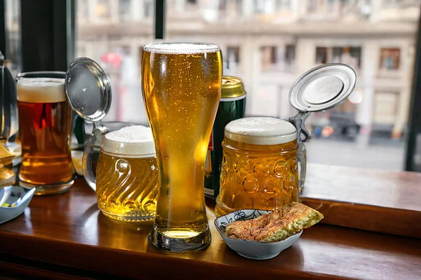 Beer in a beer glass and beer mugs stand on the window of a pub. Beer.