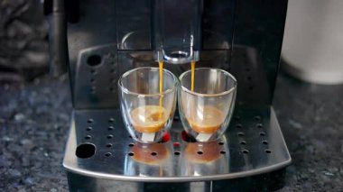 Modern bir kahve makinesi, şeffaf bardaklara lezzetli Espresso kahveleri doldurur. Metal destekli, yakın plan. Kahve..