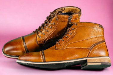 Pembe arka planda bir çift dana derisi bot. Yatay çekim. Erkek ayakkabısı fikirleri.