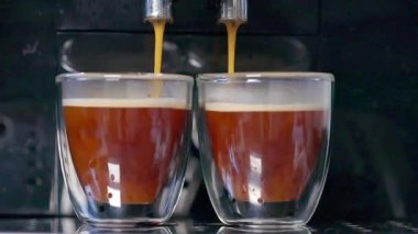 Modern bir kahve makinesi, şeffaf bardaklara lezzetli Espresso kahveleri doldurur. Metal destekli, yakın plan. Kahve..