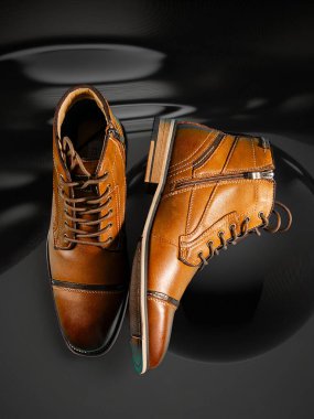 Siyah arka planda bir çift kaliteli dana derisi bot. Dikey çekim. Erkek ayakkabısı fikirleri.