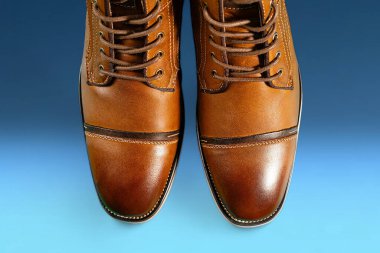 Mavi arka planda bir çift dana derisi bot. Yatay çekim. Erkek ayakkabısı fikirleri.