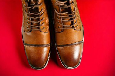 Kırmızı arka planda bir çift dana derisi bot. Yatay çekim. Erkek ayakkabısı fikirleri.