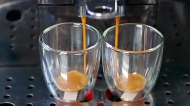 Modern bir kahve makinesi, şeffaf bardaklara lezzetli Espresso kahveleri doldurur. Metal destekli, yakın plan. Kahve..
