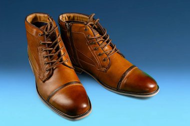 Mavi arka planda bir çift dana derisi bot. Yatay çekim. Erkek ayakkabısı fikirleri.
