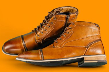 Sarı arka planda bir çift kaliteli dana derisi bot. Yatay çekim. Erkek ayakkabısı fikirleri.