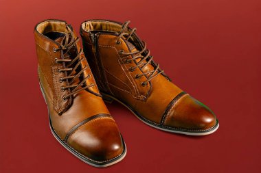 Kırmızı arka planda bir çift dana derisi bot. Yatay çekim. Erkek ayakkabısı fikirleri.