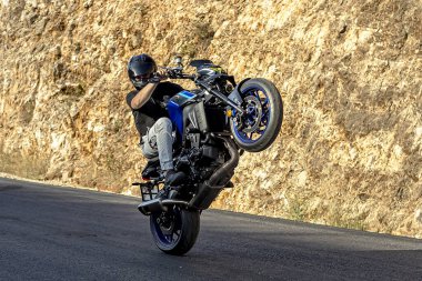 Bir motosiklet yarışçısı motosikletinde zor ve tehlikeli bir gösteri sergiler. Motosikletin arka tekerine binmek. Aktarım.