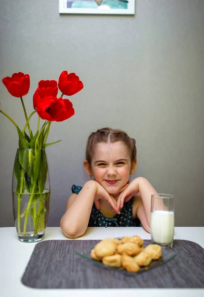 小女孩拿着面包坐在桌旁 — 图库照片