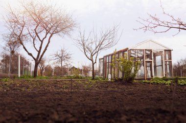 Serası ve ağaçları olan sebze bahçesi.