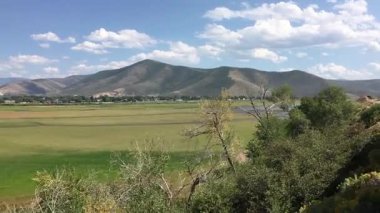 Heber Valley Utah hareket halindeki bir trenden görülmüş. Wasatch dağ sırası ve yeşil çayır. Utah 'ta aydınlık bir yaz gününde batıda hareket halindeki bir trenin camından el kamerasıyla çekilmiş..