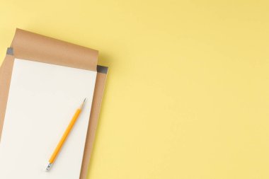 Sarı arka planda kurşun kalemle birlikte el sanatları defterini aç. Üst görünüm.