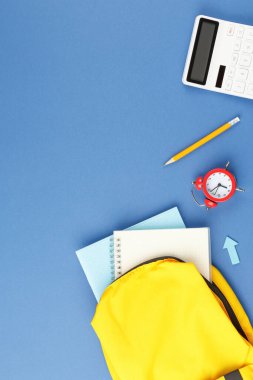 Okul konseptine geri dönelim. Mavi arka planda okul malzemeleriyle dolu sırt çantası. Düz yatıyordu.