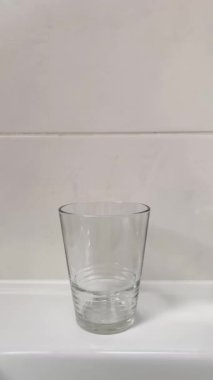 Bir kadının eli, bambu diş fırçalarını cam bardağa koyar. 4K dikey video. Banyo da biyolojik çözünebilir hijyen ürünleri var..
