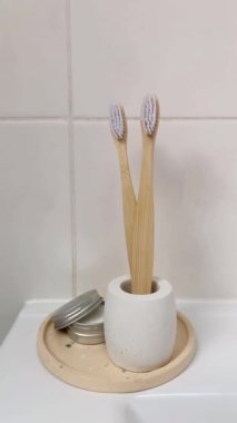 Beton bir stantta bambu diş fırçaları. Diş macunu tozu. 4K dikey video. Banyo da biyolojik çözünebilir hijyen ürünleri var..