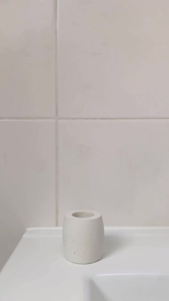 女性の手は コンクリートスタンドに竹の歯ブラシを置きます 垂直ビデオ バスルーム内の生分解性衛生製品 — ストック動画
