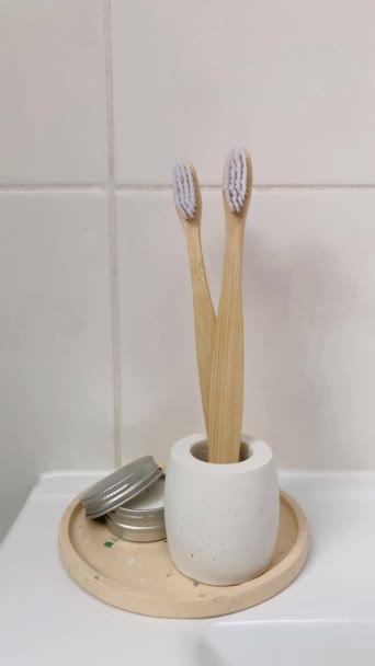 コンクリートスタンドの竹の歯ブラシ 歯磨き粉について 垂直ビデオ バスルーム内の生分解性衛生製品 — ストック動画