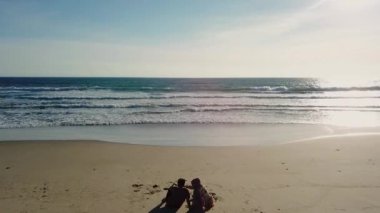 Pandeglang, Endonezya - 22 Temmuz 2022: Pandeglang Endonezya 'da günbatımının tadını çıkaran genç mutlu çiftin hava manzarası. Tatil gençliği konsepti. Drone görünümü 