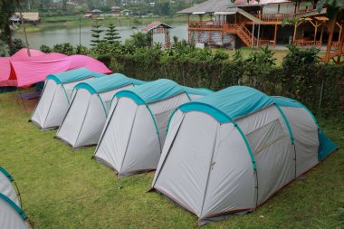 Nehir kenarında kamp ve çadır. Panoramik manzara. Ağaçları ve yeşil otları olan doğal alan. Kamp çadırı. Kamp alanı