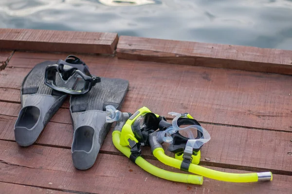 Full set of Scuba Diving equipment with selective focus on wooden pier. Fins, Depth Gauge, Balanced Regulator,Power Inflator, Dive Mask and Snorkel. Scuba gear and accessories.
