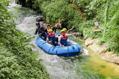 Pangalengan, Bandung-Endonezya Aralık 2022: Bir grup erkek ve kadın nehir üzerinde rafting yapıyorlar, ekstrem ve eğlenceli spor. Bir grup insan su sporları rafting