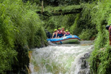 Pangalengan, Bandung-Endonezya Aralık 2022: Bir grup erkek ve kadın nehir üzerinde rafting yapıyorlar, ekstrem ve eğlenceli spor. Bir grup insan su sporları rafting