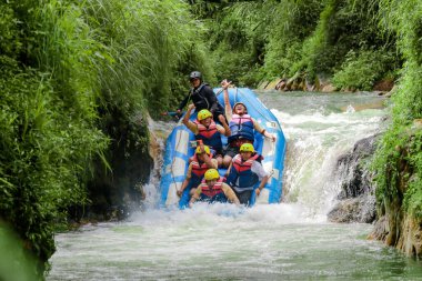 Pangalengan, Bandung-Endonezya Aralık 2022: Bir grup erkek ve kadın nehir üzerinde rafting yapıyorlar, ekstrem ve eğlenceli spor. Bir grup insan su sporları rafting